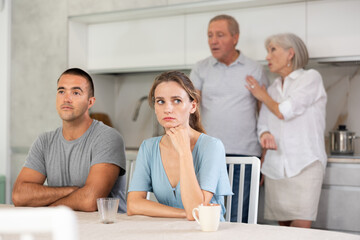 Wall Mural - Portrait of an offended married couple in a home kitchen, which mature family members reprimand. Family conflict