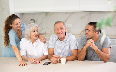 Wall Mural - Young married couple and senior parents talk about home life