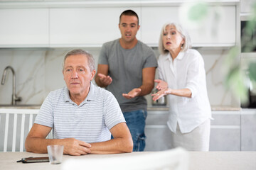 Wall Mural - Elderly woman and adult man during family quarrel with elderly man in kitchen