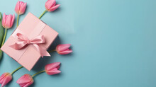 Mother's Day Decorations Concept. Top View Photo Of Blue Giftbox With Ribbon Bow And Bouquet Of Pink Tulips On Isolated Pastel Pink Background With Copyspace. Holiday Web Banner. Top View. Tenderness