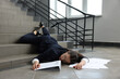 © New Africa - Unconscious woman with scattered folder and papers lying on floor after falling down stairs indoors