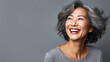 portrait of rich classy older beautiful asian lady in 50's smiling in front of grey background