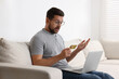 © New Africa - Emotional man with credit card and laptop on sofa at home. Be careful - fraud