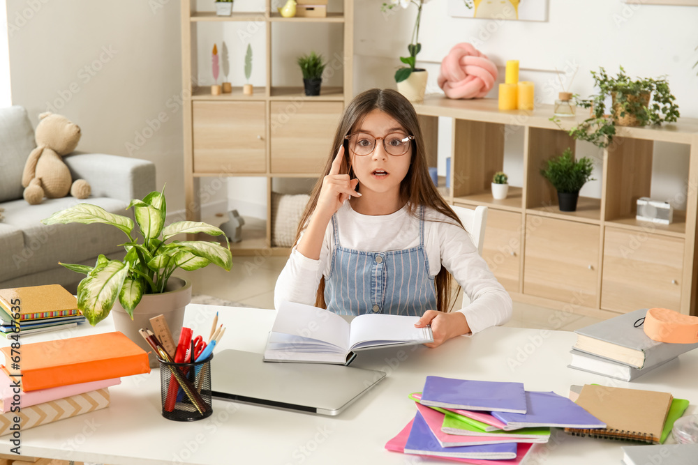 Little girl reading schoolbook at home