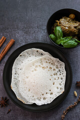 Poster - Appam, Kerala breakfast food duck curry or hot and spicy chickpea Masala and milk tea chai, Christian breakfast on dark black background. fermented rice pan cake. Top view of Indian veg food.