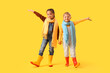 © Pixel-Shot - Little children in rubber boots holding hands on yellow background
