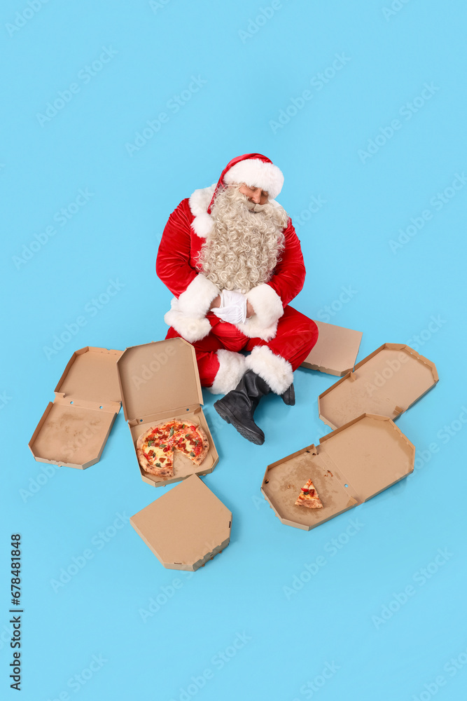 Santa Claus with tasty pizza on blue background