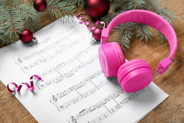 Wall Mural - Composition with music sheets, modern headphones and Christmas decorations on wooden background, closeup