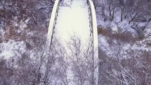 Winter Snow Flyover Of Long Abandoned Bridge Over Small Frozen River