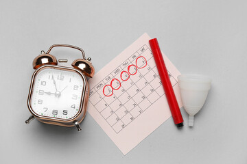 Wall Mural - Composition with menstrual calendar, cup and alarm clock on grey background