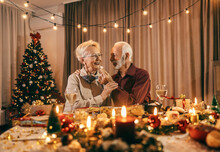 A senior man is feeding his wife with cookie at christmas table on christmas and new year's eve at home.