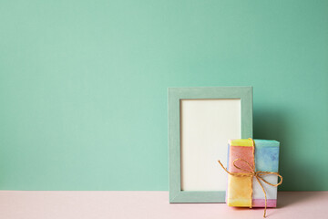 Wall Mural - Picture frame and gift box on pink table. mint green wall background. copy space