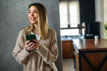 Canvas Print - Smiling young woman chatting in social networks, working, using mobile applications at home.