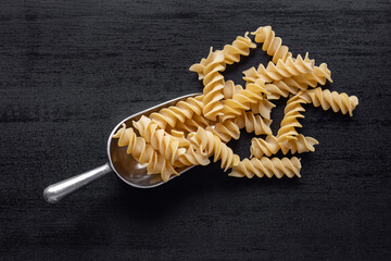 Wall Mural - Uncooked fusilli pasta. Uncooked italian pasta in scoop. Top view.