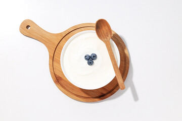 Sticker - Bowl with yogurt with berries on board and wooden spoon on white background, top view