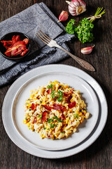 Wall Mural - macaroni and cheese with corn, bacon topped with panko breadcrumbs on plates on dark wooden table with ingredients at background, vertical view