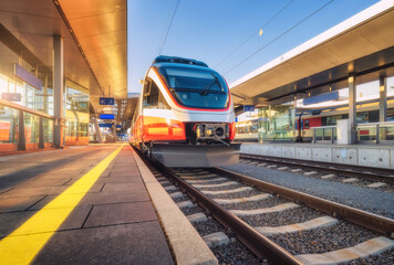 Wall Mural - High speed train on the modern railway station at sunset in summer in Graz, Austria. Beautiful orange intercity passenger train on the railway platform. Railroad. Passenger railway transportation