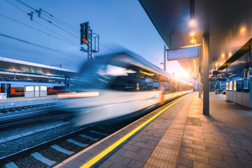 Wall Mural - blurred high speed train on the modern railway station at night in graz, austria. fast moving interc