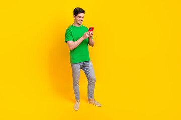 Sticker - Full size photo of good mood guy wear stylish t-shirt denim pants look at smartphone read notification isolated on yellow color background