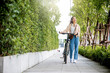 © sorapop - Lifestyle Asian young woman walking alongside with bicycle on summer in countryside outdoor, Happy female smiling walk down the street with her bike on city road, ECO environment, healthy travel