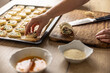 © weyo - The cook places raw mini puff pastry cookies on a baking sheet.