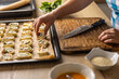© weyo - The cook places raw mini puff pastry cookies on a baking sheet.