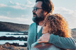 Romantic people man and woman hugging and admiring beautiful landscape panorama together. Travel couple enjoying outdoor romance activity with wind turbines in background. Couple in love outdoor