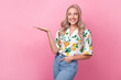 Portrait of toothy beaming woman with wavy hair wear stylish shirt arm presenting offer look empty space isolated on pink color background