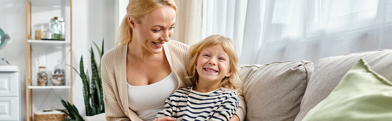 happy mother hugging daughter in casual attire and sitting together on couch in living room, banner