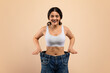© Prostock-studio - Weight Loss Result. Happy Young Indian Woman Posing In Oversized Jeans