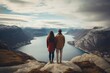Couple standing on the edge of a cliff and looking at the fjord, rear view of Couple family traveling together on cliff edge in Norway, AI Generated