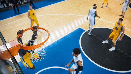 Wall Mural - Cinematic College Basketball Tournament: Two Young Successful Diverse Teams Play a Championship Match in a Modern Arena. Excited African Player Scores a Slam Dunk with Two Hands and Hangs on a Hoop