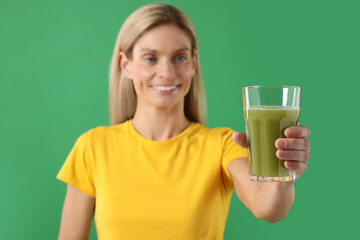 Poster - Woman with glass of tasty celery juice on green background, selective focus