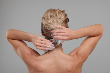 Poster - Woman washing hair on light grey background, back view