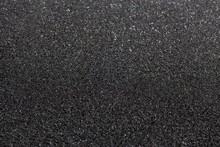 Black foam rubber. Closeup full-frame macro background with selective focus and shallow depth of field.