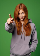Wall Mural - young red-haired girl in a purple hoodie points with her finger, teenager, student, color background, beautiful woman, fashion, style, portrait, hairstyle, face, pointing gesture