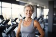 Mature woman in the gym after training. She stands and looks at the camera smiling. Keeping fit over 50. Smiling Caucasian woman come to exercise in fitness studio.