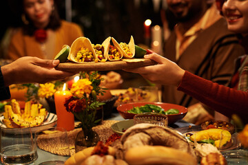 Wall Mural - Close-up of people sitting at table and eating traditional food during celebration of holiday