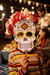 Wall Mural - Vertical portrait of little girl in skull mask looking at camera during celebration of holiday