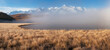 Beautiful sunny foggy morning in the mountains. Autumn frost on dry grass. Snowy peaks. North Chuysky Range and Lake Dzhangyskol. Russia, Altai Republic. Panoramic view.