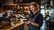© MP Studio - A cafe worker, wearing an apron and using a smartphone, standing at the counter of a warmly lit cafe with coffee equipment in the background.