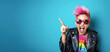 Young woman with colourful dyed hair, sunglasses,  cheeky attitude, smiling and pointing finger up to side. Wide banner, copy space. Generative AI