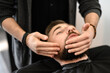 A barber massages and rubs a male client beard after applying moisturizing oil