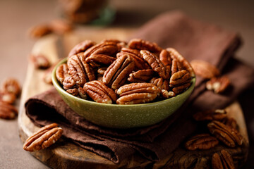 Wall Mural - Pecan nuts in a bowl on a brown background