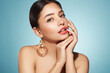 © Oleg Gekman - Portrait of beautiful young woman on blue background, red lipstick and festive makeup, Christmas toy earrings, shiny glowing skin, Winter holidays concept
