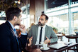 © Davor - Mature businessman mentoring younger colleague in cafe meeting