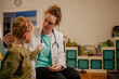 A friendly pediatrician is talking to a little boy at her home medical visit.