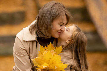 Wall Mural - Happy family on an autumn walk. Mother and daughter walking through the park and enjoying the beautiful autumn nature.