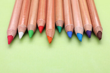 Poster - Many colorful pastel pencils on light green background, closeup and space for text. Drawing supplies