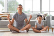 Young man with his little son meditating at home
